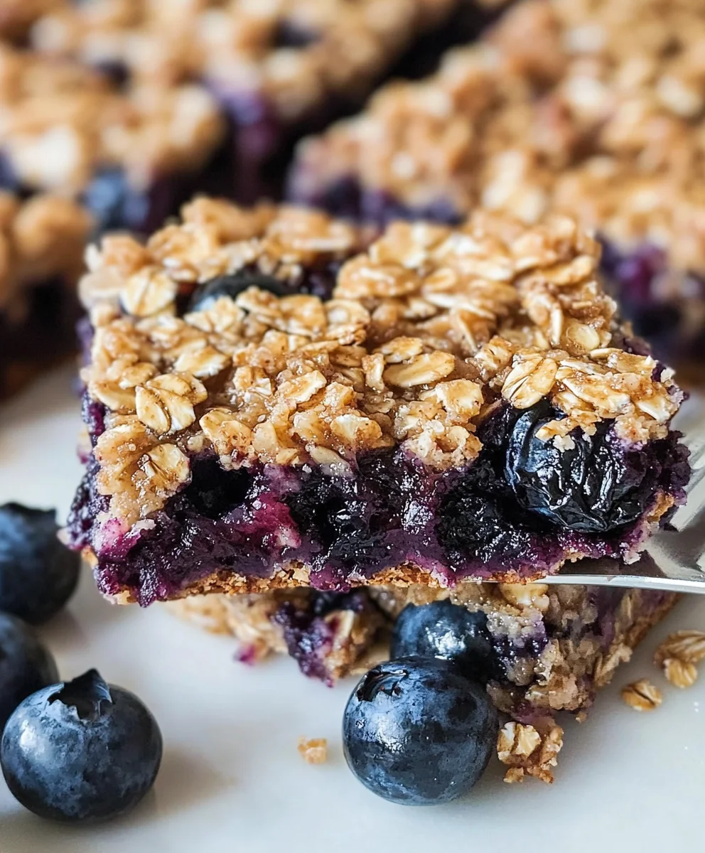 Close-up of chewy blueberry oatmeal breakfast bars with fresh blueberries.