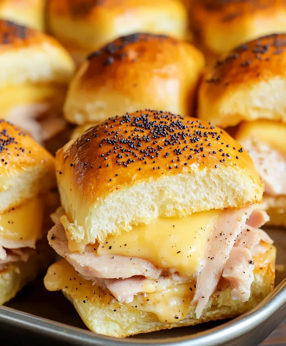Cheesy turkey sliders on Hawaiian rolls with poppy seeds on top, fresh out of the oven.