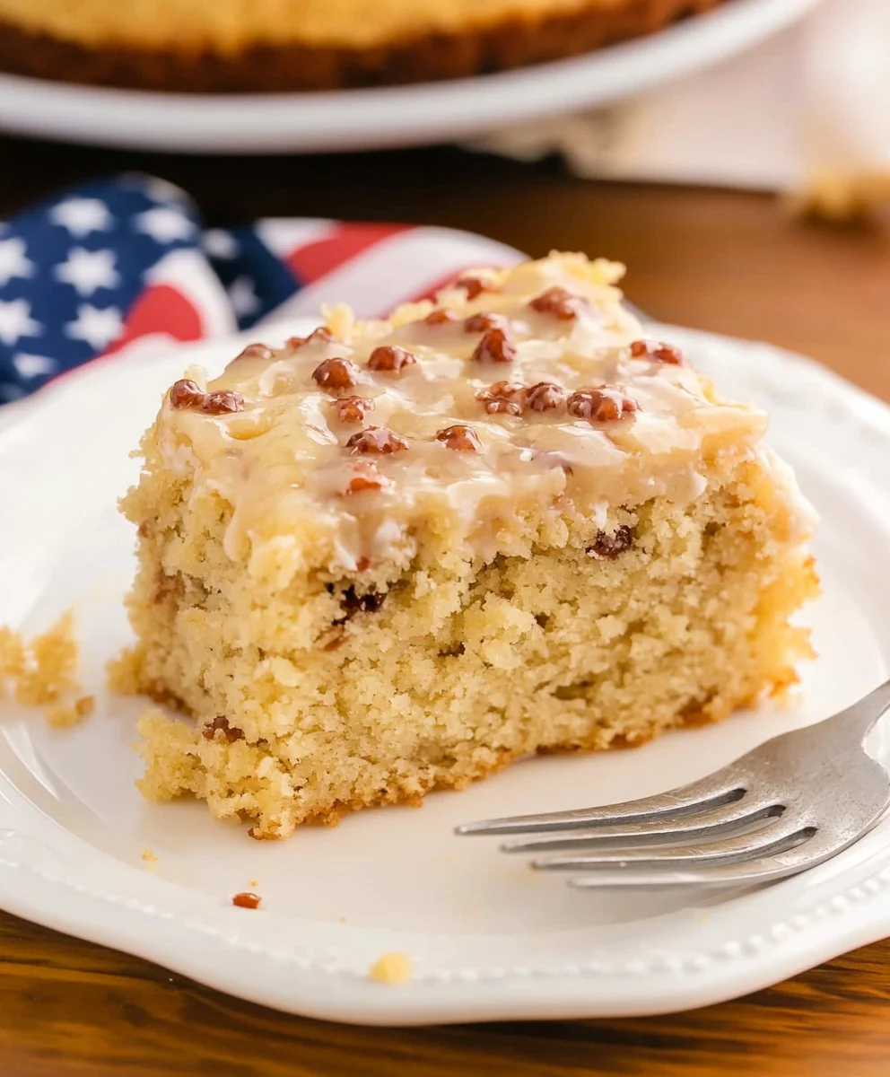 Slice of moist God Bless America Cake with caramel pecan coconut icing on a white plate