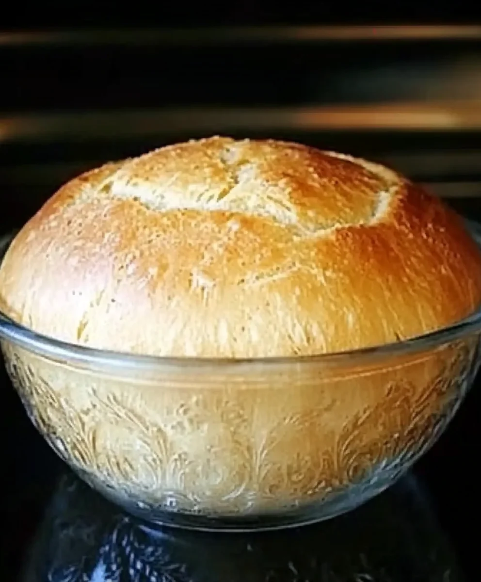 Homemade peasant bread baked in a glass Pyrex bowl with a golden crust