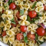 Overhead view of Bow Tie Pasta Salad with cherry tomatoes, spinach, red onion, and basil tossed in pesto dressing